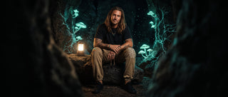 Model seated on a boulder in a glowing mycelium cave, wearing khaki Paradigm snow wash heavyweight joggers