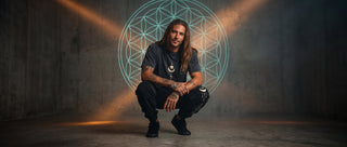 Model crouching in a concrete chamber under a glowing Flower of Life projection, wearing black Existential snow wash heavyweight joggers