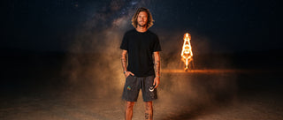 Model in charcoal Existential mineral wash waffle knit shorts in the desert at night beside a glowing sculpture