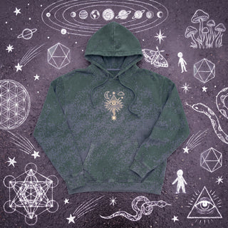 Forest Green Mystic Signal snow washed heavyweight cotton hoodie laid flat on wet chalk-covered pavement, front view with the cream all-seeing eye in a radiating pyramid printed center chest above the kangaroo pocket.