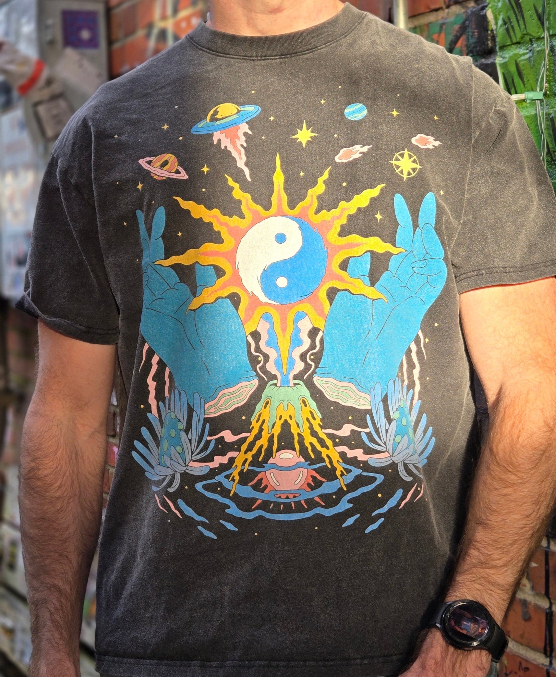 Close-up of man wearing charcoal washed Yin Yang tee showing sun mystical hands and volcano design detail