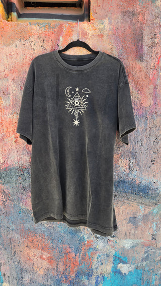 Mystic Signal charcoal vintage tee front on hanger showing small all-seeing eye chest graphic against colorful wall