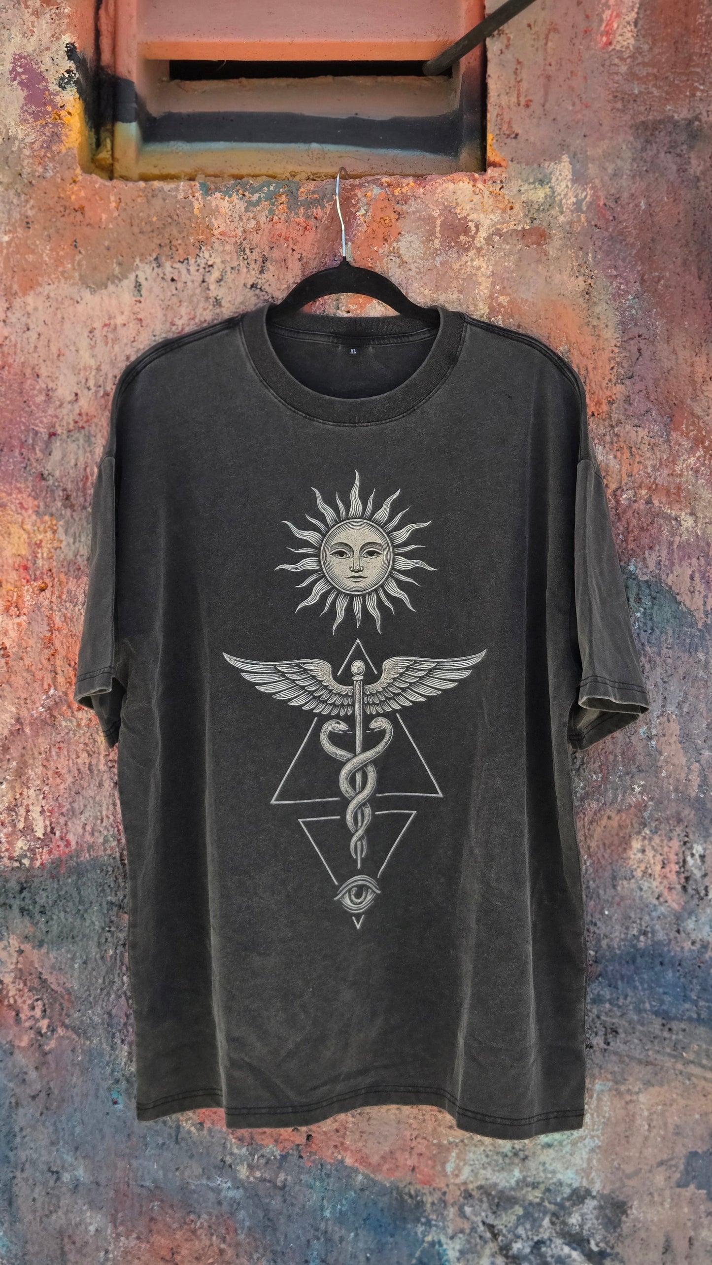 Inner Alchemy Fluffy Vintage tee hanging against weathered colorful wall showing caduceus print
