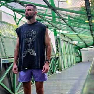 Man wearing Dimensional Drift snow wash raw hem tank on green pedestrian bridge