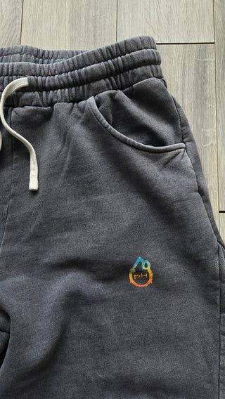 Hip detail of the washed gray Spirit Molecule sweatpants, showing the teal to orange pH flame logo beside the side pocket