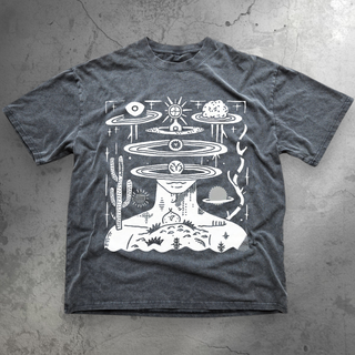 Flat lay of washed charcoal gray Spaced Out t-shirt with white surreal desert and cosmic orbit graphic on concrete