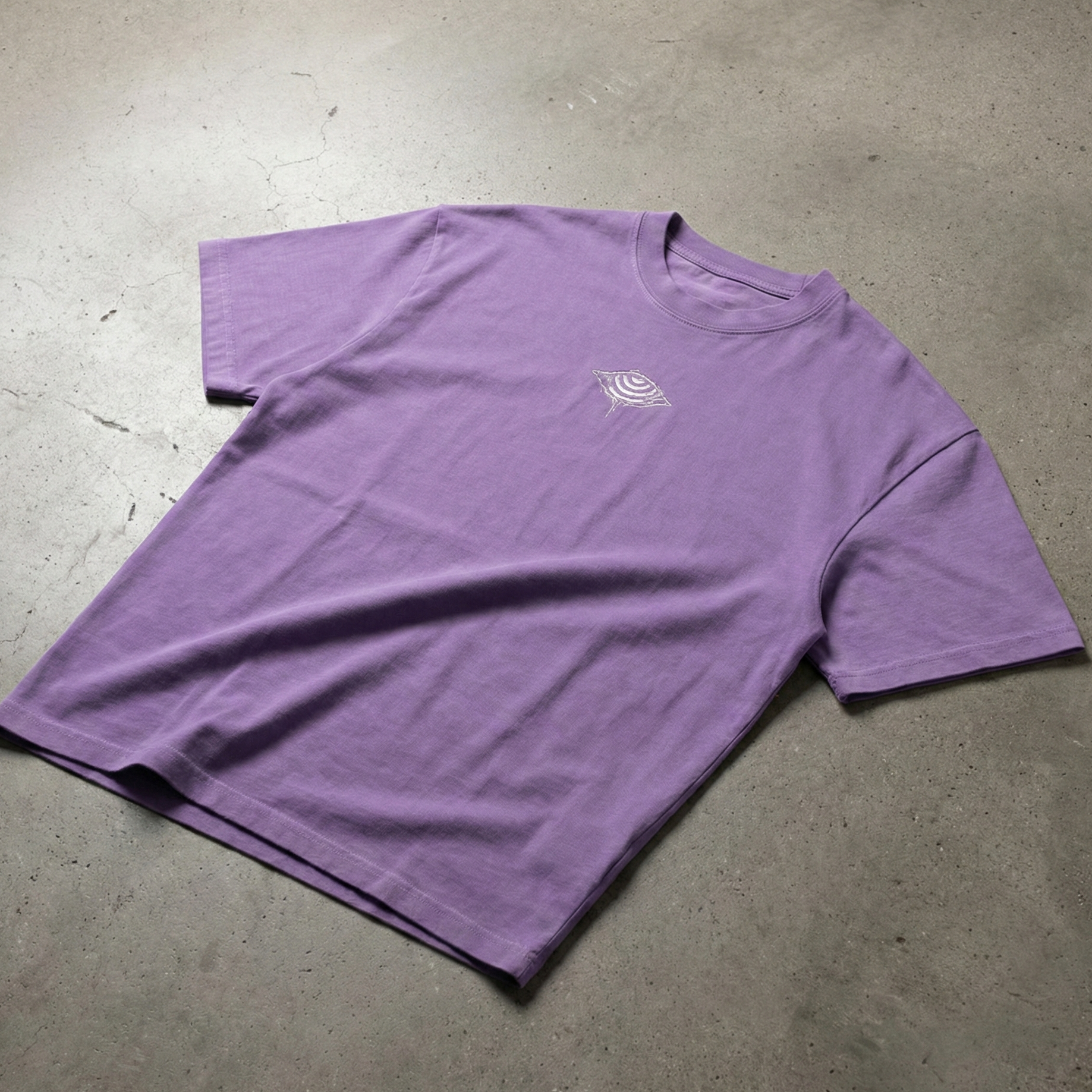 Purple Embrace The Chaos vintage wash tee on concrete with small eye logo on chest