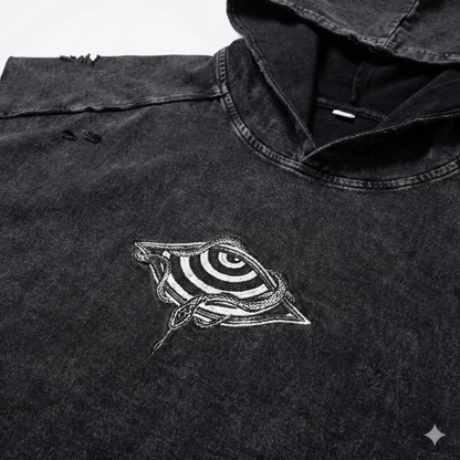 Close-up of embroidered chest logo showing spiraling eye wrapped in snakes on snow wash fabric