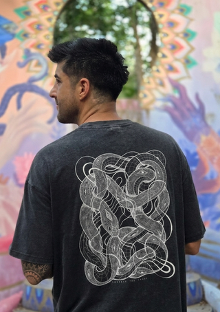 Man wearing a black t-shirt with a white snake design in front of a colorful mural.