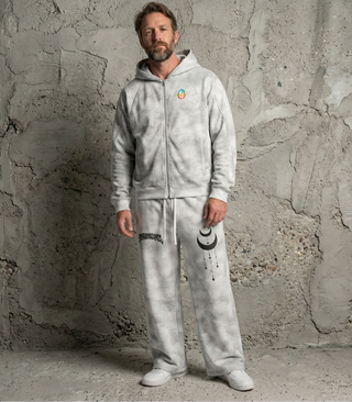 Model wearing grey dirty wash Existential sweatpants with moon and stars paired with zip hoodie