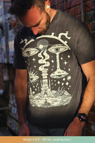 Model looking down showing full front graphic of surreal eyes and mushrooms on charcoal wash Paradoxical Perspective tee