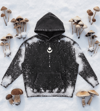 Black Existential snow wash hoodie with moon graphic laid flat on snow with mushrooms