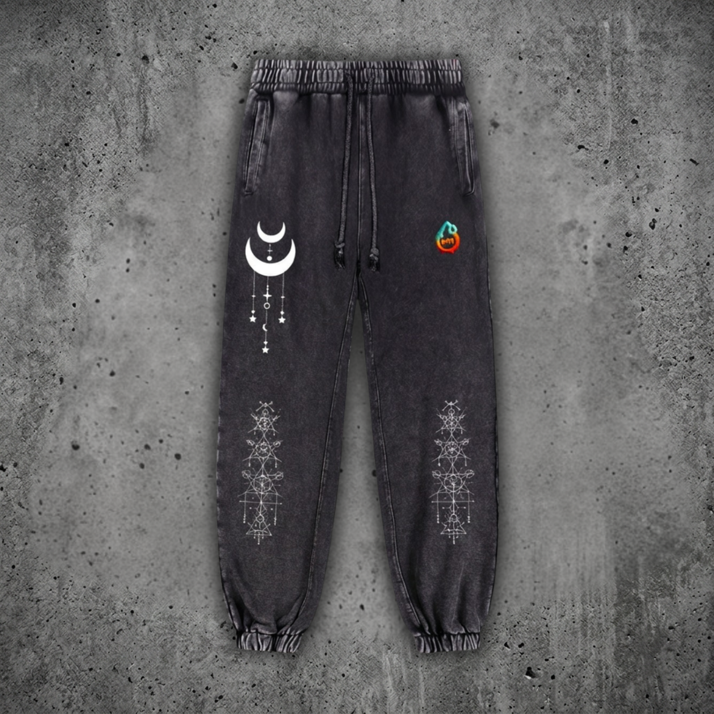 Charcoal snow wash Existential heavyweight joggers on concrete, with drawstring waist and cuffed ankles, printed with a cream crescent moon and white sacred geometry on the legs.