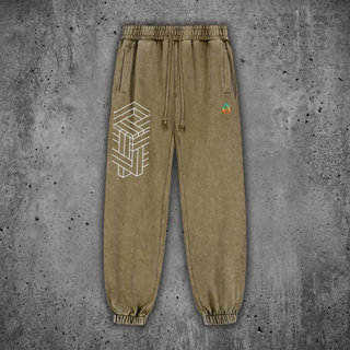 Olive green snow wash Paradigm heavyweight joggers on concrete, with drawstring and cuffed ankles, printed with a white impossible-geometry cube on one leg and the colorful Phantasmagorical logo on the other.