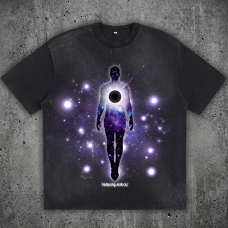 Charcoal Void Eclipse sun fade loose fit tee on concrete, printed with a galaxy-filled silhouette figure, a black eclipse orb at the chest and glowing stars.