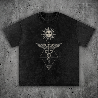 Charcoal snow wash Inner Alchemy oversized heavyweight tee on concrete, printed in cream with a radiant sun face, a winged caduceus of twin snakes and an all-seeing eye.