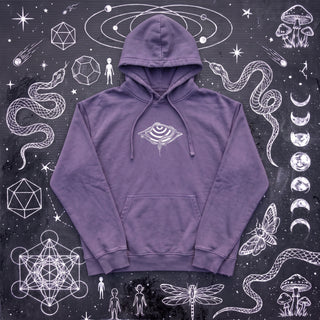 Lavender purple Embrace The Chaos snow washed loose cotton hoodie laid flat on wet chalk-covered pavement, front view with the small white striped eye in a wide diamond and a snake printed center chest, a Patakota collab.