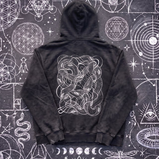 Black Beauty Embrace The Chaos snow washed loose cotton hoodie laid flat on wet chalk-covered pavement, back view with the white tangled serpent knot print, a Patakota collab.