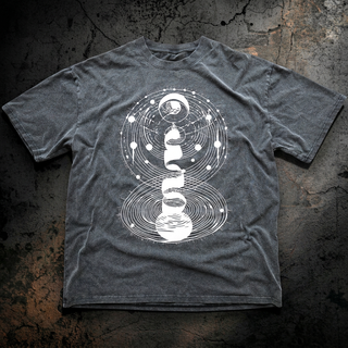 Dark gray Cosmic Connection fluffy vintage heavyweight tee on cracked concrete, printed with white line art of orbiting planets, a crescent moon and cosmic spirals.