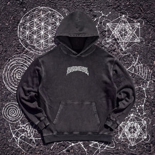 Front of the Cosmic Geometry snow washed heavyweight cotton hoodie in Black Beauty, styled on dark asphalt covered in white chalk sacred geometry, showing the small white wavy Phantasmagorical wordmark arched across the chest and the kangaroo pocket.