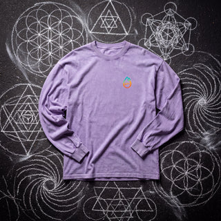Front of the Dimensional Drift acid wash oversized long sleeve tee in Purple, styled on dark asphalt covered in white chalk sacred geometry, with the Phantasmagorical logo on the left chest.