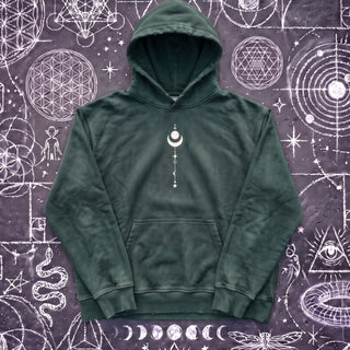 Blackish green Existential snow wash hand-frayed heavyweight hoodie laid flat on wet chalk-covered pavement, front view with the kangaroo pocket and the small cream crescent moon and star stack printed on the chest.