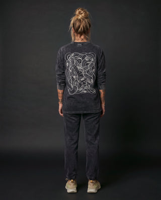 Model wearing the Embrace The Chaos acid wash relaxed fit long sleeve in Black Beauty, back view, showing the full back artwork.