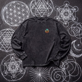 Front of the Embrace The Chaos acid wash oversized long sleeve tee in Black Beauty, styled on dark asphalt covered in white chalk sacred geometry, with the Phantasmagorical logo on the left chest.