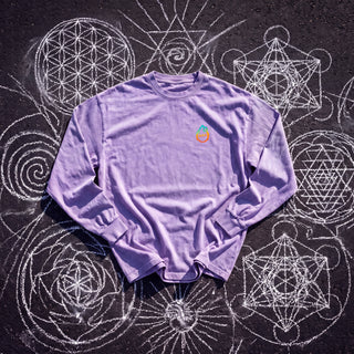 Front of the Embrace The Chaos acid wash oversized long sleeve tee in Purple, styled on dark asphalt covered in white chalk sacred geometry, with the Phantasmagorical logo on the left chest.