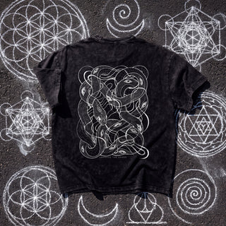Back of the Embrace The Chaos Patakota collab tee in black snow wash on chalk sacred geometry, printed in white line art with a dense tangle of intertwined serpents and eyes above the words Embrace The Chaos.