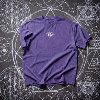Front of the Embrace The Chaos Patakota collab tee in Purple Haze snow wash on chalk sacred geometry, with a small white hypnotic eye and coiled serpent graphic at the chest.
