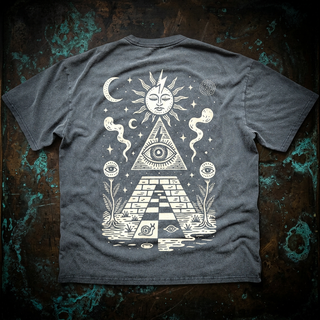 Charcoal Future Pyramids fluffy vintage washed tee, back view on weathered metal, printed in cream with a sun face, all-seeing eye in a pyramid, checkerboard path and floating eyes.