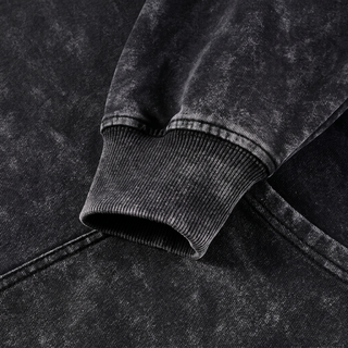 Close-up of the ribbed sleeve cuff on the black snow washed Mystic Signal heavyweight cotton hoodie, showing the dense rib and the pale mineral wash breaking across the raised ribs.