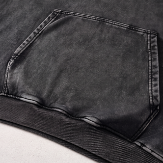 Close-up of the kangaroo pocket and ribbed bottom hem on the black snow washed Mystic Signal heavyweight cotton hoodie, showing the angled topstitched pocket edges and snow wash fading.