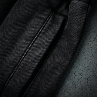 Close-up of the side seam and pocket topstitching on the Inner Alchemy heavyweight joggers, shot on dark charcoal concrete.