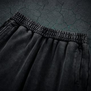 Close-up of the drawstring elastic waistband and slanted side pocket on the Inner Alchemy heavyweight joggers, shot on dark charcoal stone.