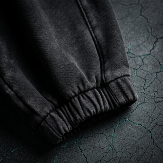 Close-up of the ribbed elasticated ankle cuff on the Inner Alchemy heavyweight joggers, shot on dark charcoal stone.