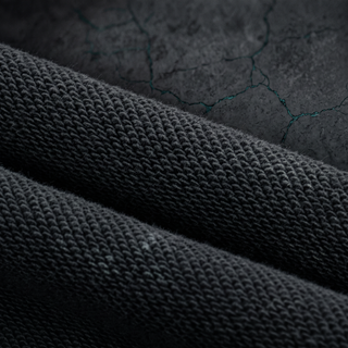 Macro of the 420 GSM heavyweight cotton knit grain on the Inner Alchemy joggers, raking light showing the loop structure.
