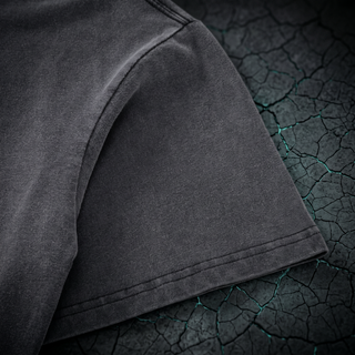 Close-up of the dropped shoulder seam and short sleeve hem on a Phantasmagorical fluffy vintage washed heavyweight tee, shot on dark charcoal stone.