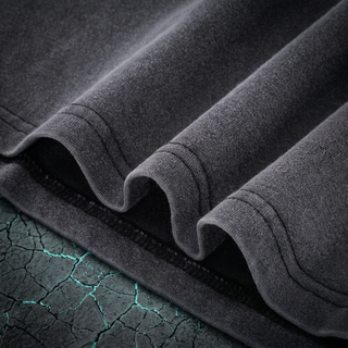 Close-up of the layered bottom hem and double-needle stitching on a Phantasmagorical fluffy vintage washed tee, shot on dark charcoal stone.