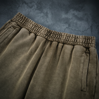 Close-up of the drawstring elastic waistband and slanted side pocket on the Paradigm heavyweight joggers, shot on a weathered bluestone wall.