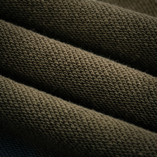Macro of the 420 GSM heavyweight cotton knit grain on the Paradigm joggers, raking light showing the loop structure.