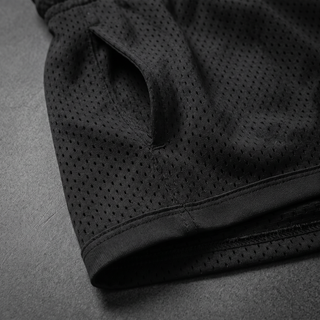 Close-up of the side pocket opening and flat-knit hem binding on the black Nomenclature mesh shorts