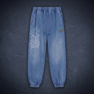 Paradigm 420 GSM heavyweight joggers in Royal Blue mineral snow wash, laid straight on dark charcoal slate, showing the drawstring elastic waistband, slanted side pockets, ribbed ankle cuffs, the white impossible-geometry cube printed on the thigh and the pH flame logo on the hip.