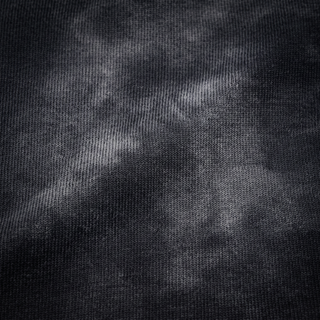 Macro of the 250 GSM heavyweight cotton knit on the black snow wash tee, raking light showing the loop structure and the mottled mineral wash.