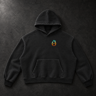 Studio flat lay of the black PsySquatch vintage wash boxy fleece hoodie on charcoal concrete, front view, showing the 390 GSM fleece, kangaroo pocket, ribbed cuffs and hem, and the small cyan to orange drop mark on the chest