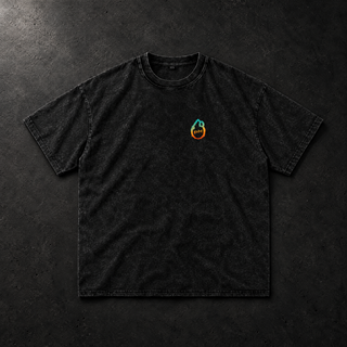 Studio flat lay of the black PsySquatch snow wash oversized tee on charcoal concrete, front view, raking softbox light picking up the mineral wash mottle, soft fabric wrinkles and contact shadows, small cyan to orange drop mark on the left chest
