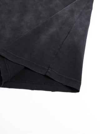 Corner of the tee folded back to show the frayed hem, side seam and mottled vintage wash across the 260 GSM cotton