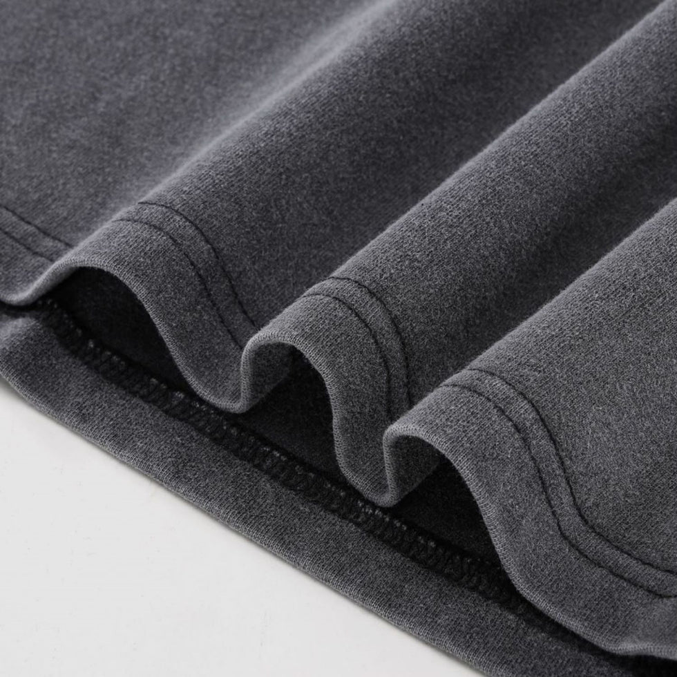 Close-up of double-stitched hem detail on charcoal gray heavyweight Yin Yang cotton t-shirt