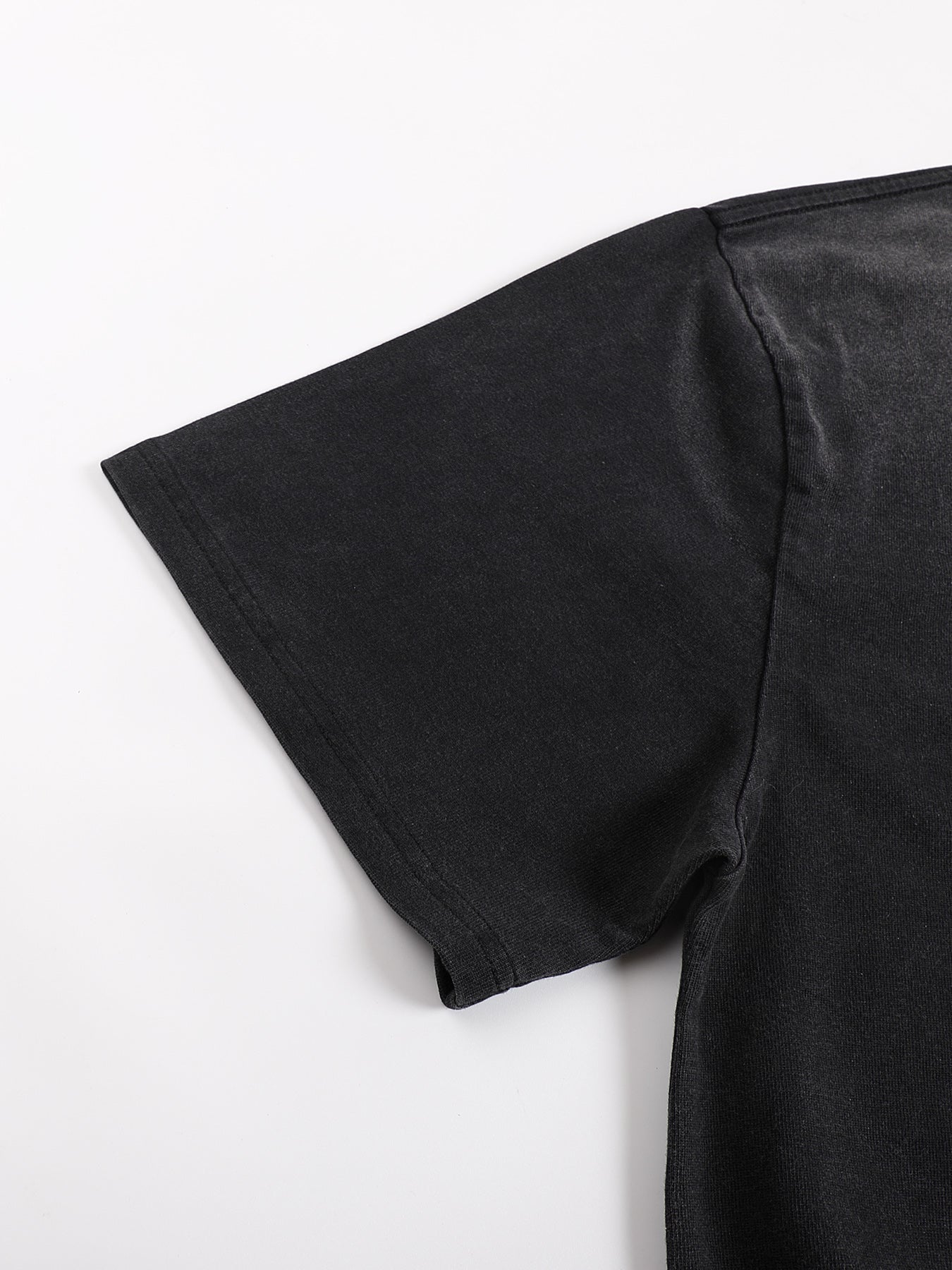 Close-up of black sunfaded Ethereal Muse tee showing drop shoulder seam and construction